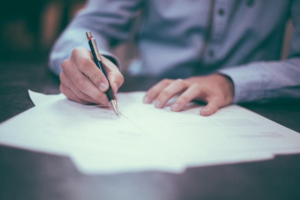 Person signing a paper document with a pen